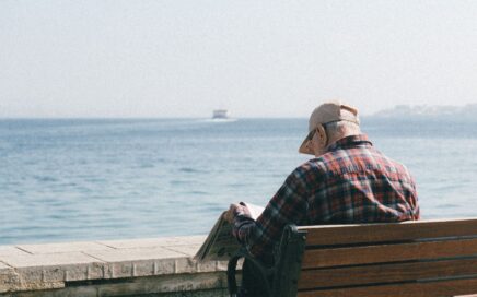 image showing older man sitting on a bench looking out to sea